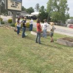 a group of people setting up garden in front of church sign