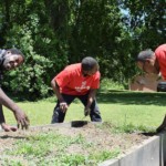 a group of people tending garden boxes in a field