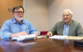2 men sitting at a board room table