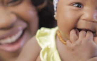woman and baby both smiling up close to the camera.